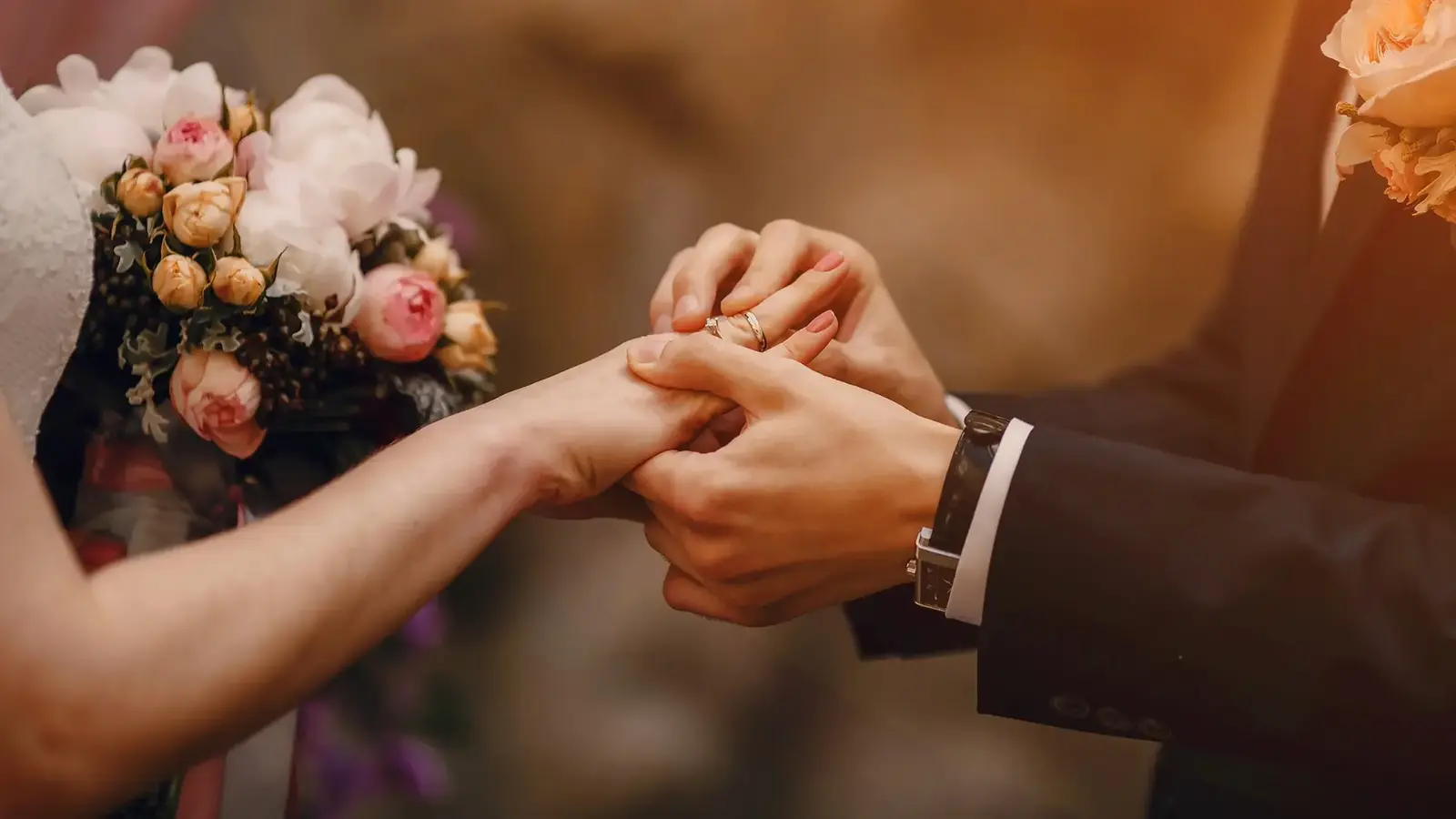 groom putting ring on bride's finger during wedding ceremony
